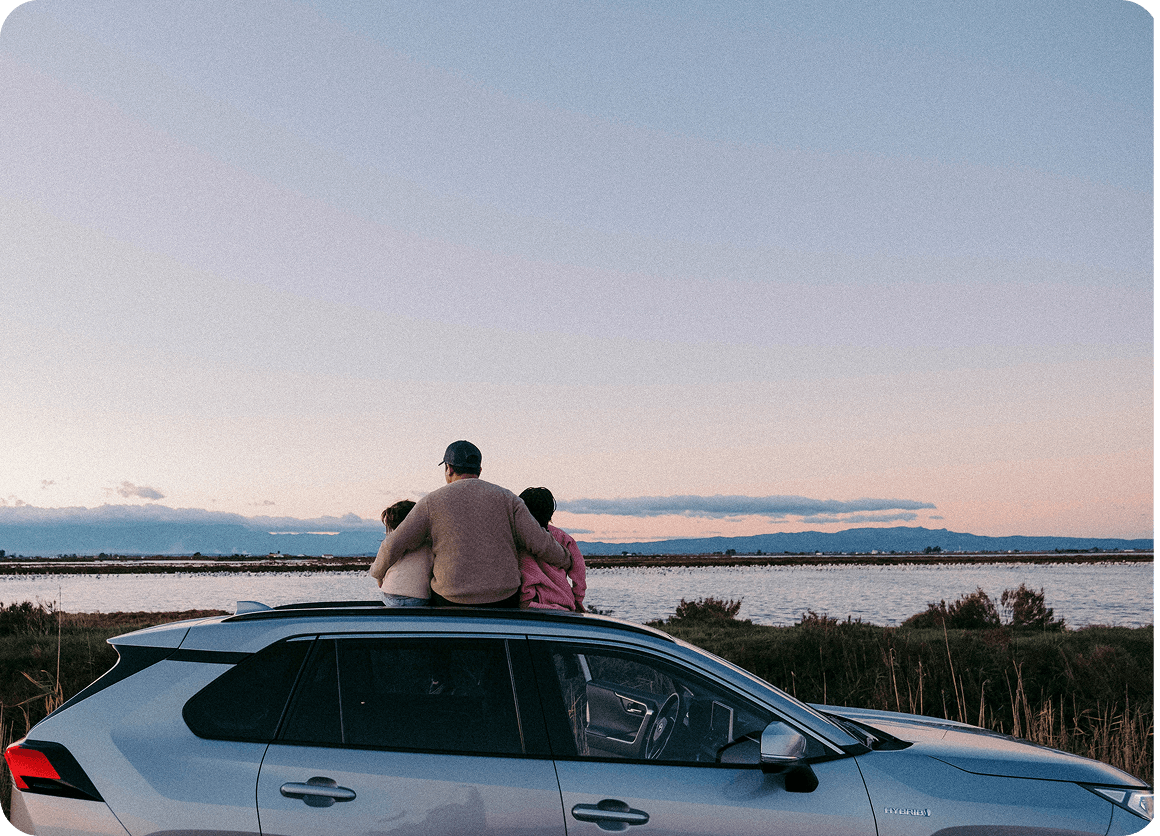 Familia mirando el atardecer sobre el coche